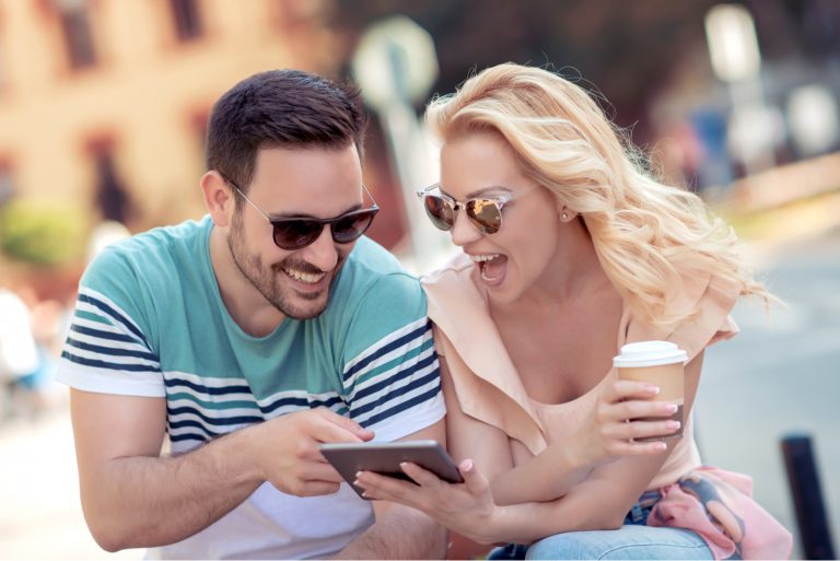 Der Mann und die Frau sitzen und schauen auf das Telefon und lachen