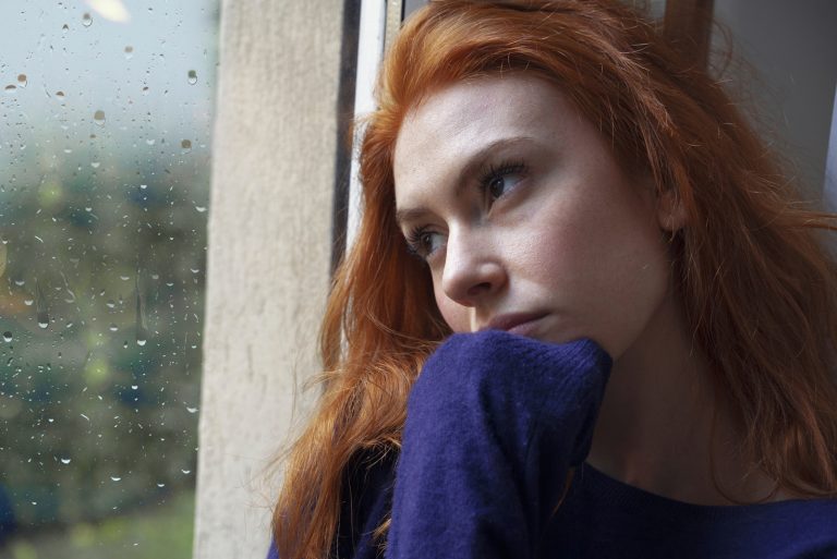 Eine imaginäre rothaarige Frau schaut aus dem Fenster