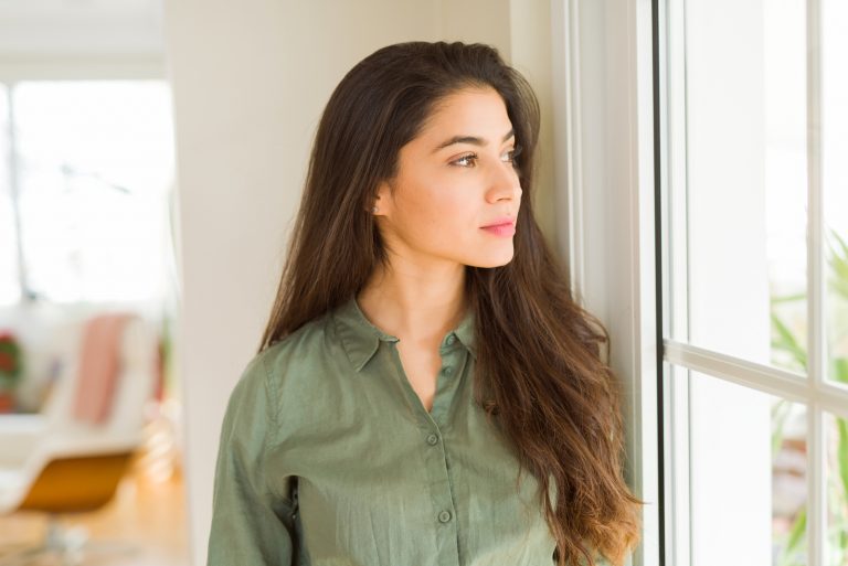 achtsame Frau, die durch das Fenster schaut