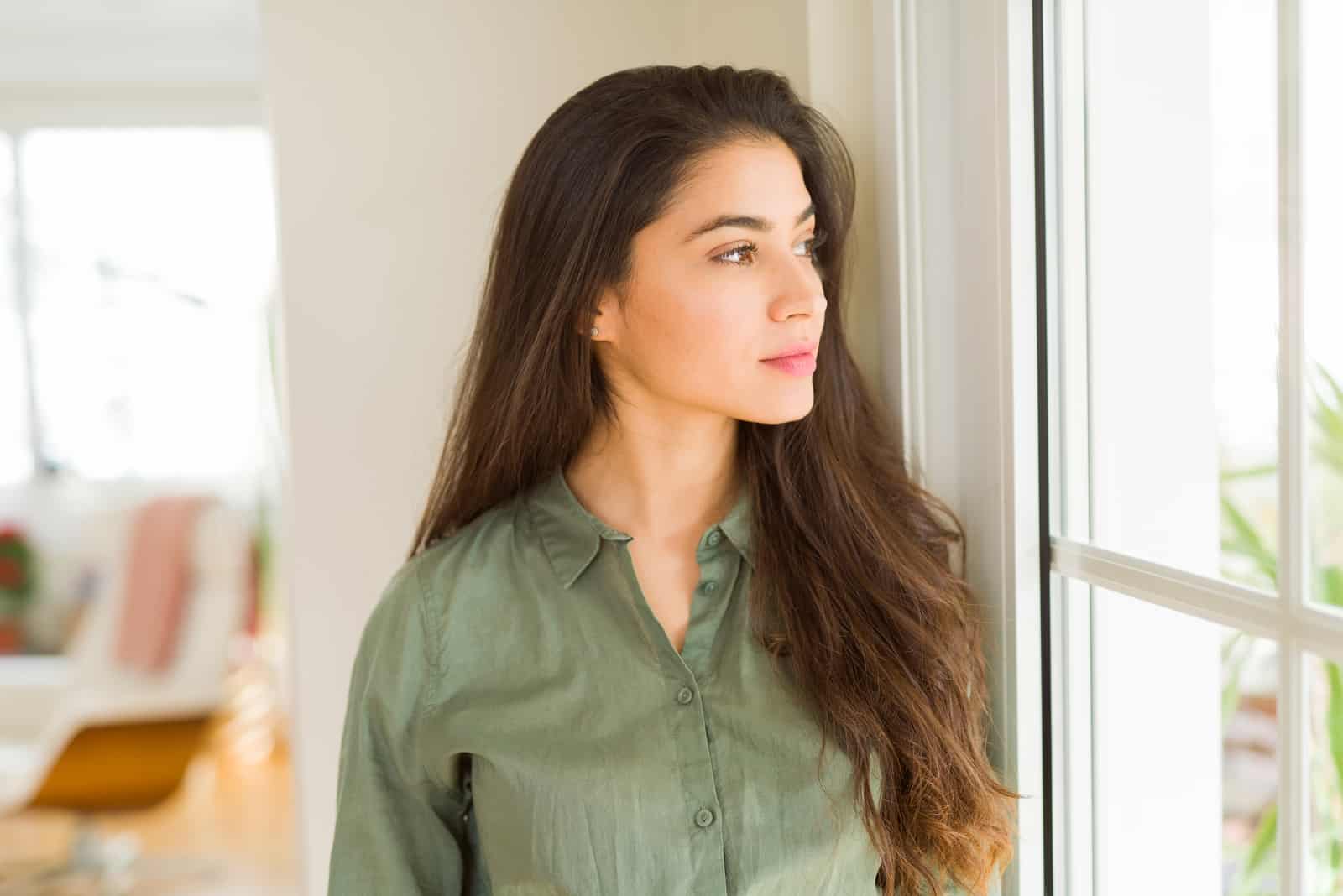 achtsame Frau, die durch das Fenster schaut