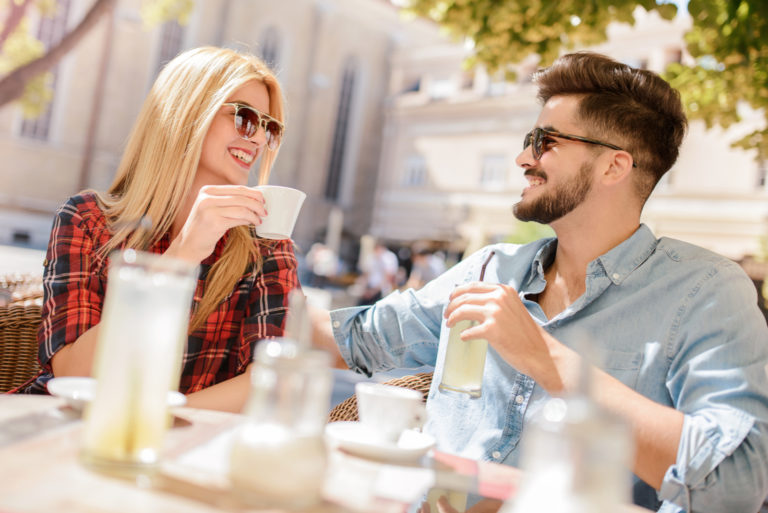 ein lächelnder mann und eine frau sitzen draußen und trinken kaffee