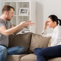 Ein Mann und eine Frau sitzen auf der Couch und streiten sich