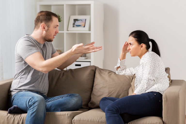 Ein Mann und eine Frau sitzen auf der Couch und streiten sich