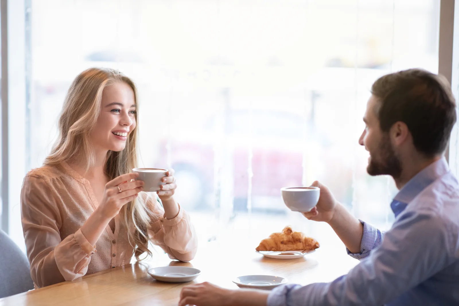 Ein lächelnder Mann und eine Frau sitzen an einem Tisch und trinken Kaffee