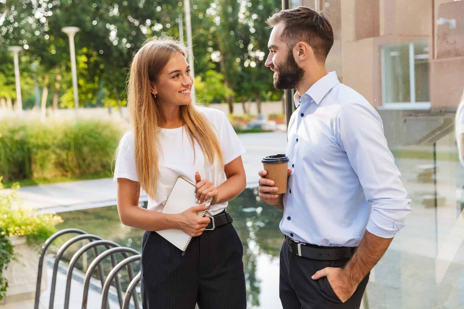 Ein lächelnder Mann und eine Frau stehen draußen und unterhalten sich