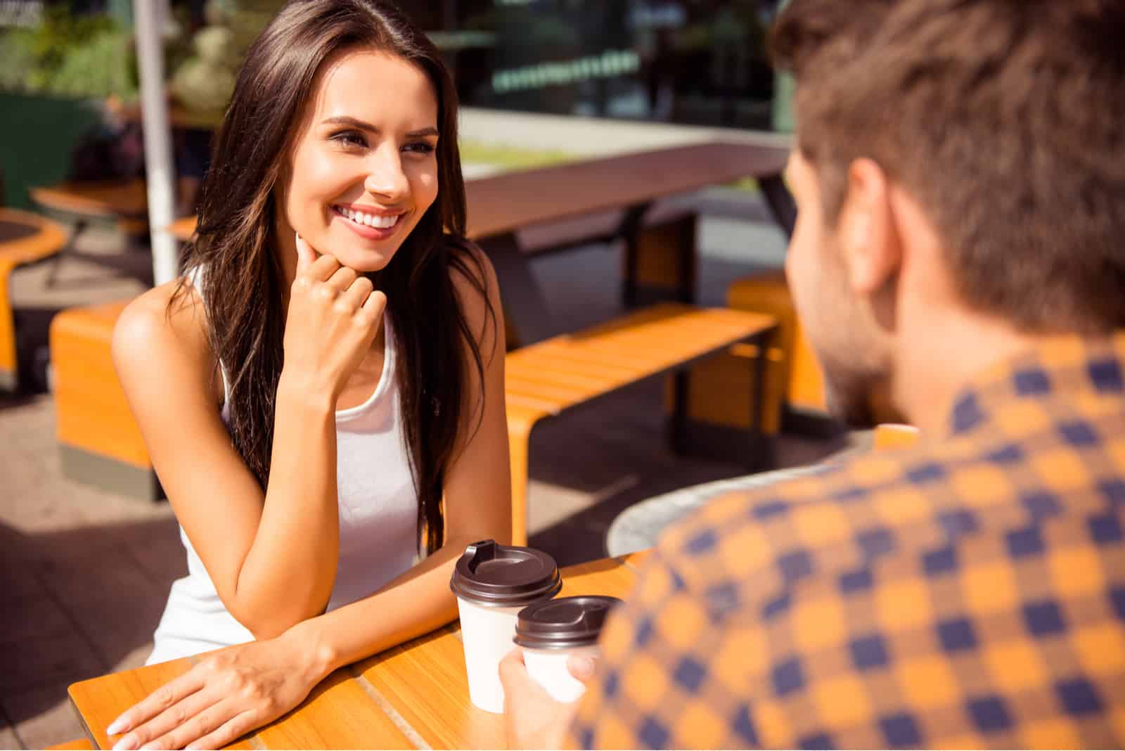 Eine lächelnde Frau mit langen schwarzen Haaren, die mit einem Mann spricht