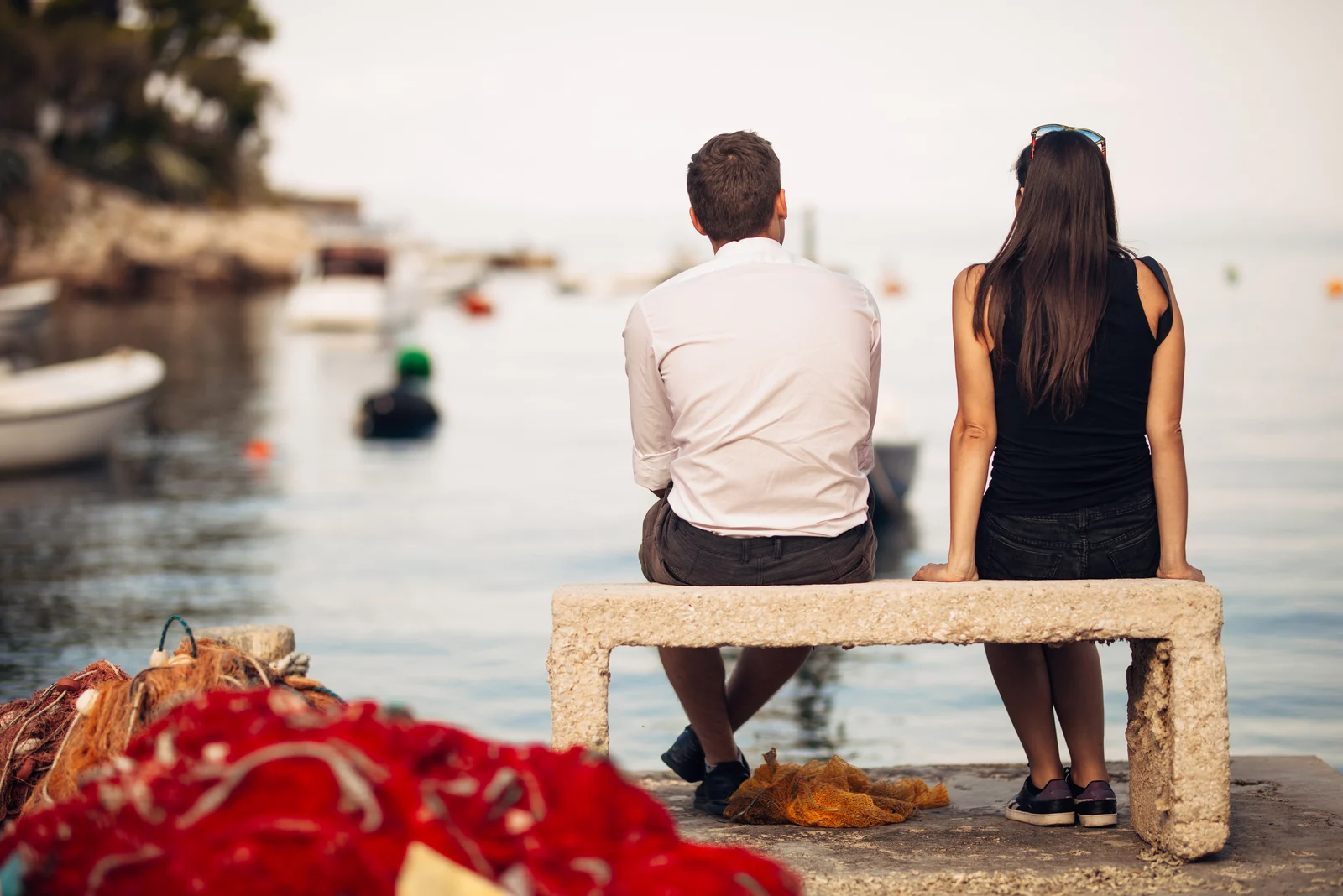 Romantisches Paar bei einem Date in der Natur, sitzend auf der Bank und Blick auf die ruhige Ozeanszene.