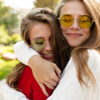 Zwei Mädchen mit Sonnenbrille umarmen sich