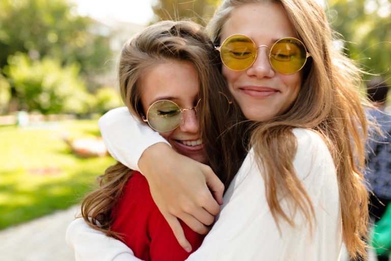 Zwei Mädchen mit Sonnenbrille umarmen sich