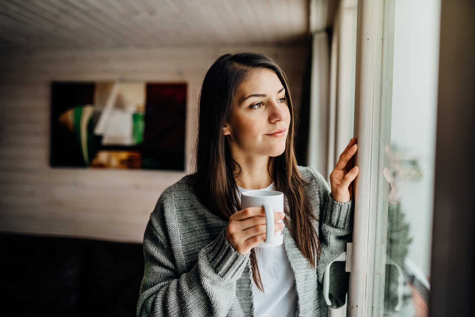 Frau trinkt Tee und schaut nach draußen