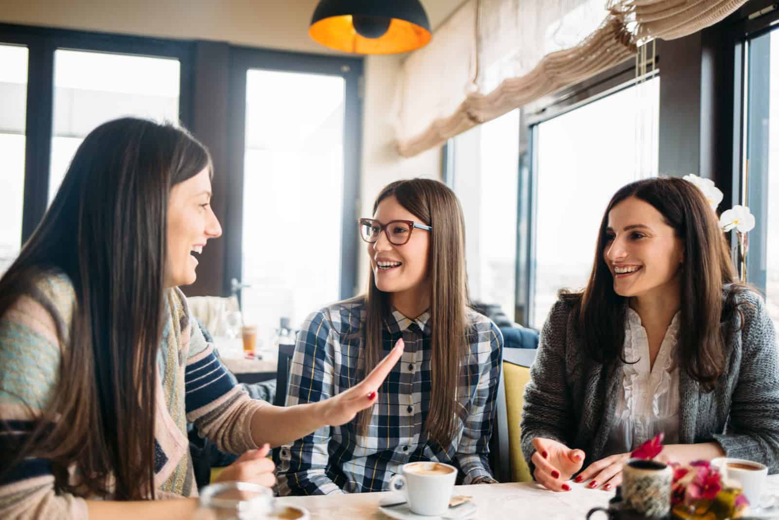 Junge Gruppe von Freundinnen sitzen in einem Café und genießen Kaffee Gespräch