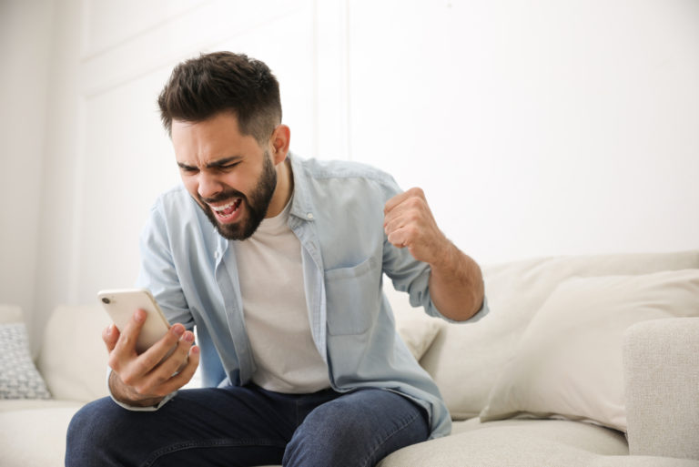 wütender Mann, der ein Mobiltelefon hält und darauf schaut