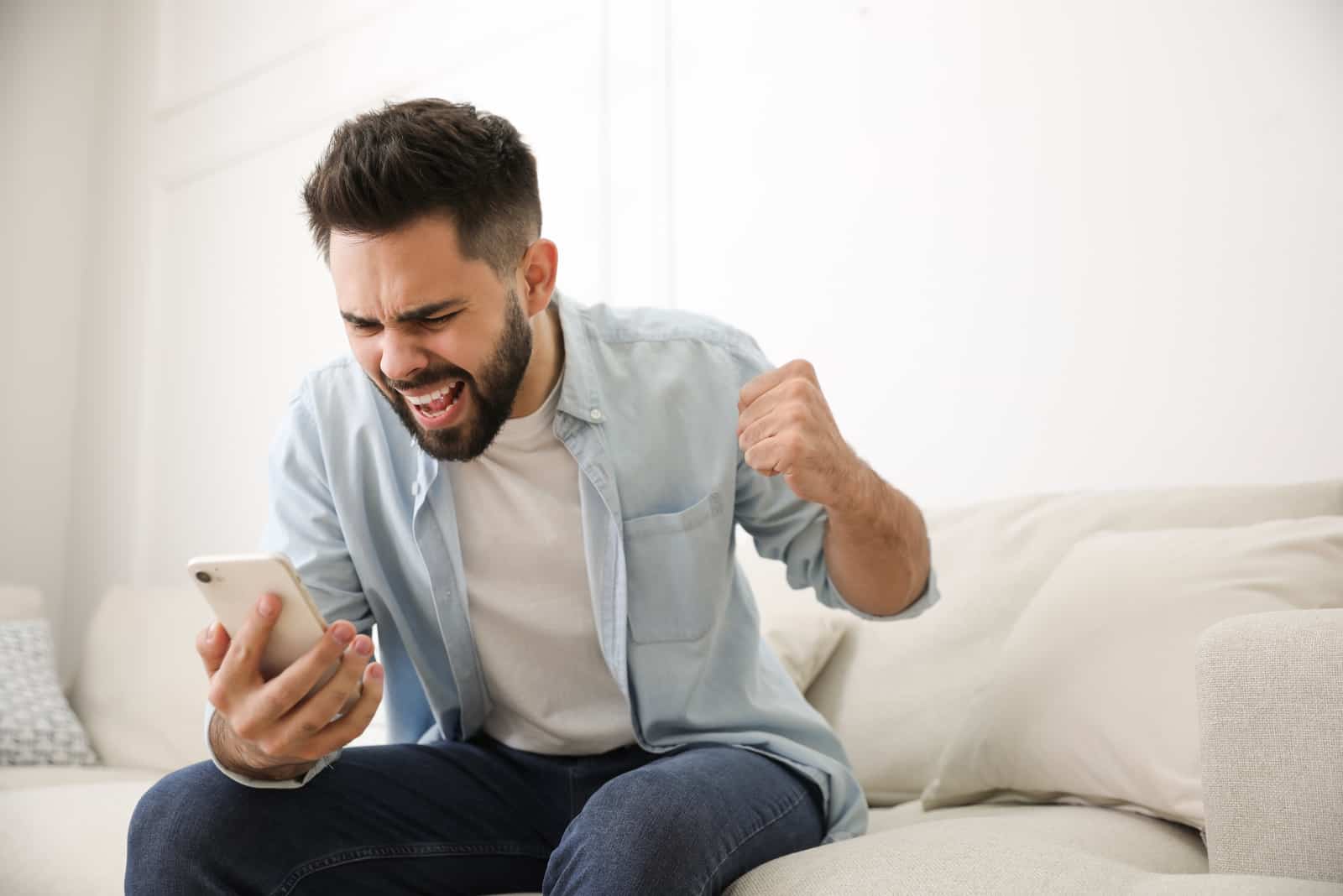 wütender Mann, der ein Mobiltelefon hält und darauf schaut