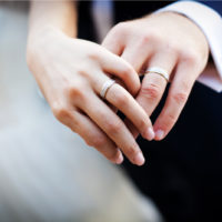 Ein Mann und eine Frau streckten ihre Hände mit Eheringen aus