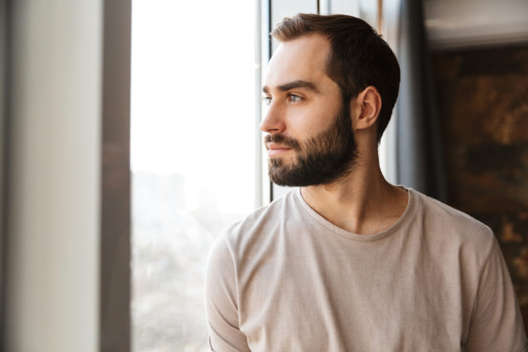 ernster Mann schaut durch das Fenster