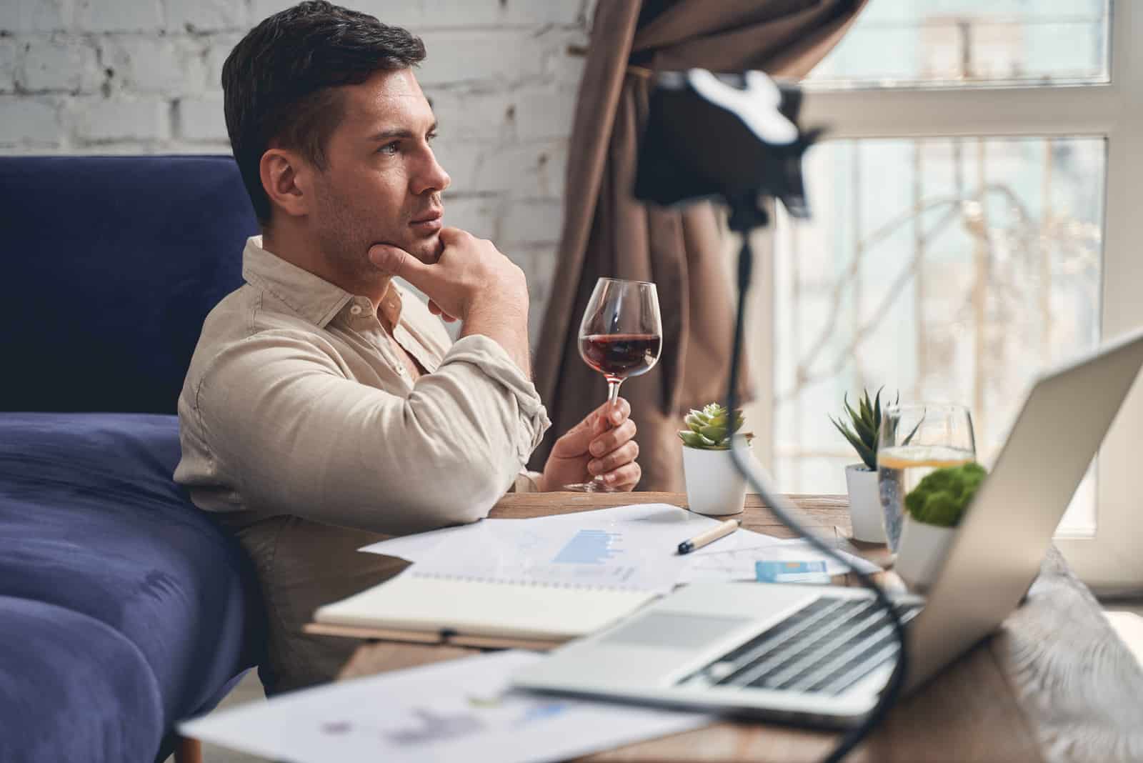 Mann, der eine Pause von der Arbeit macht, während er ein Glas Wein trinkt