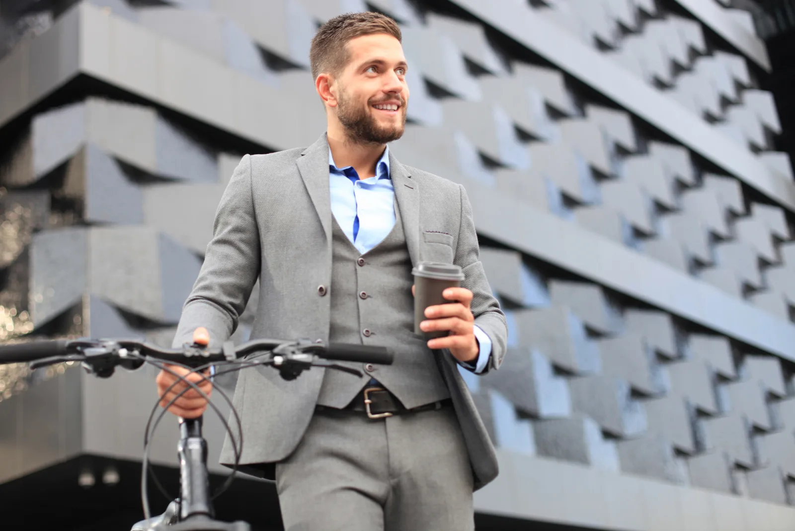 Mann im Anzug mit Fahrrad mit Kaffee