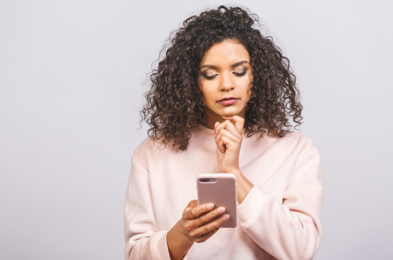 Ernste Frau, die ein Telefon hält und einen Anruf erwartet
