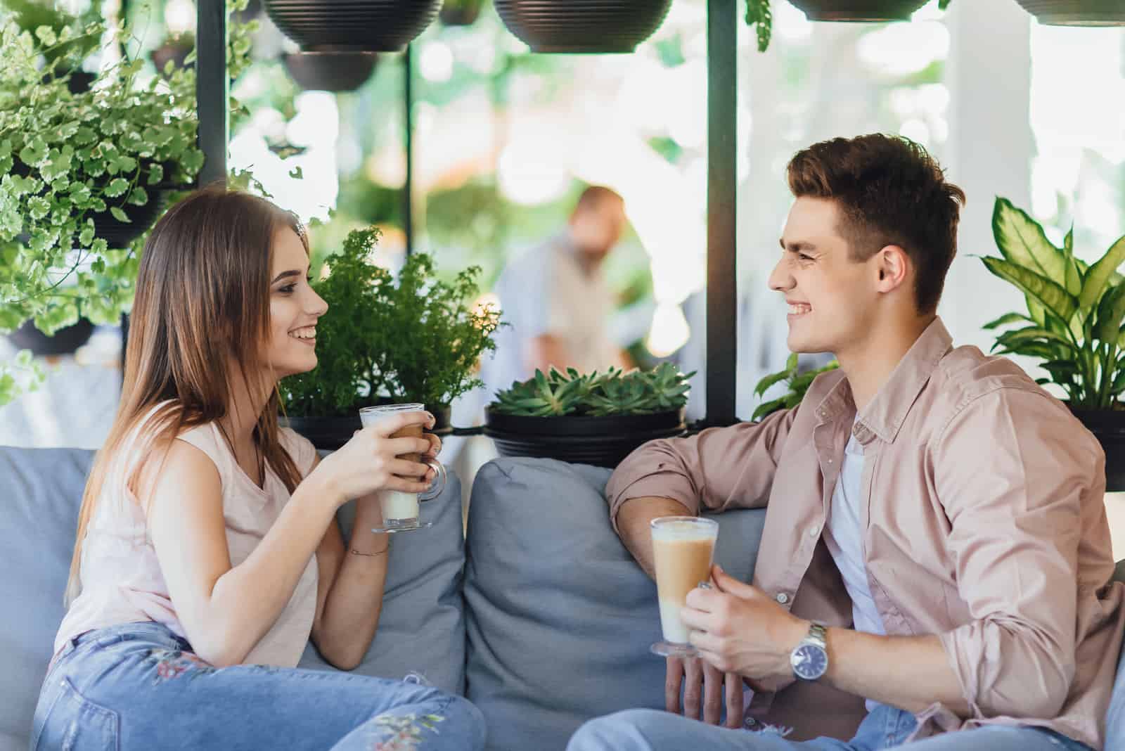 Paar sitzt auf Sofa und trinkt Kaffee