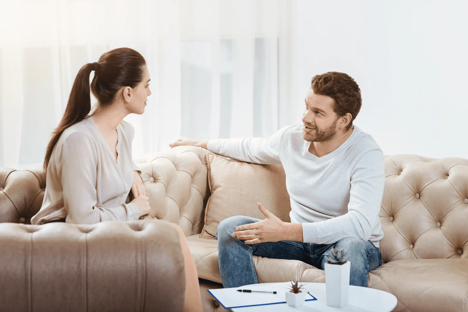Paar sitzt auf weißem Sofa und redet