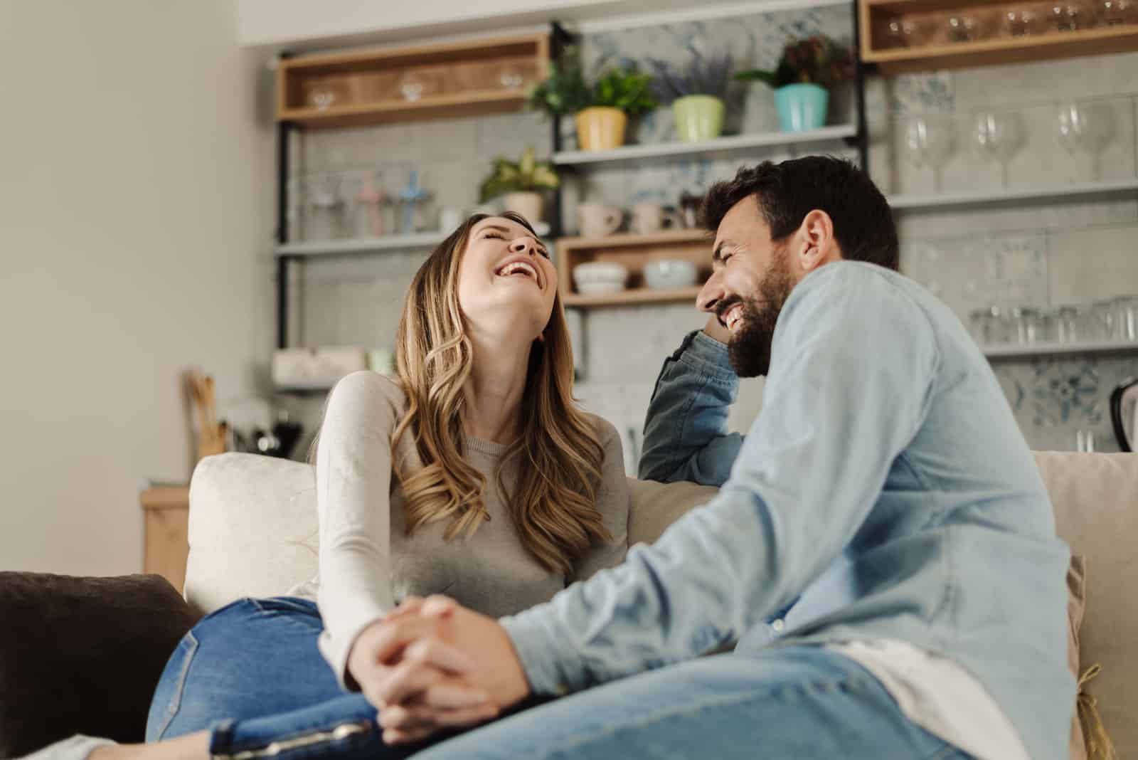 Glückliches Paar, das auf dem Sofa lacht