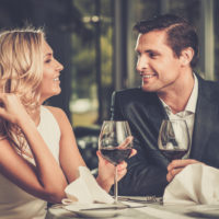eine lächelnde Frau, die mit einem Mann beim Abendessen sitzt