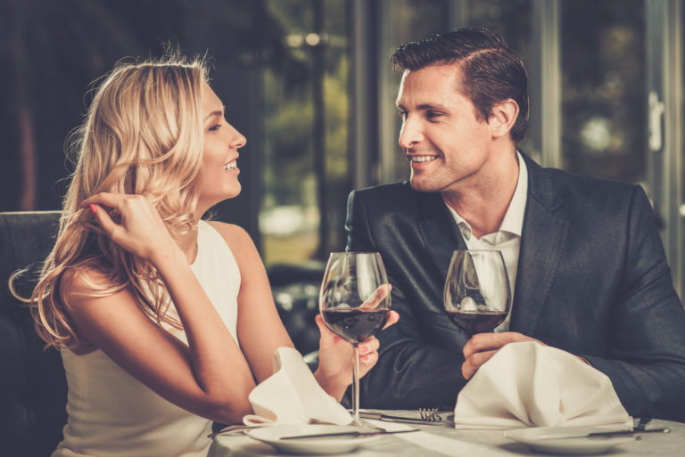 eine lächelnde Frau, die mit einem Mann beim Abendessen sitzt