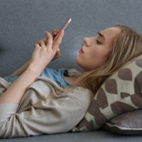 Besorgte junge Frau, die auf Smartphone schaut