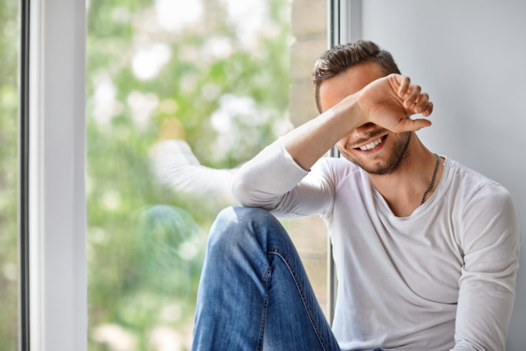 schüchterner Mann, der am Fenster sitzt