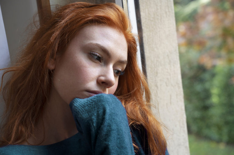 nachdenkliche frau sitzt am fenster