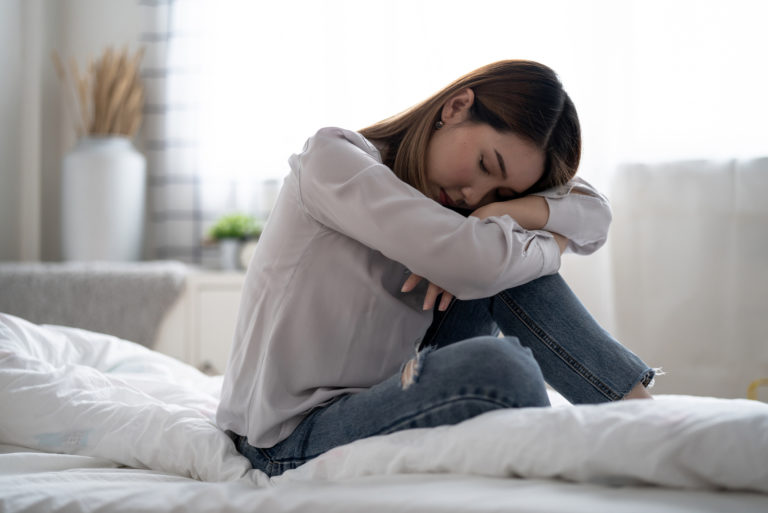 traurige Frau, die auf dem Bett sitzt