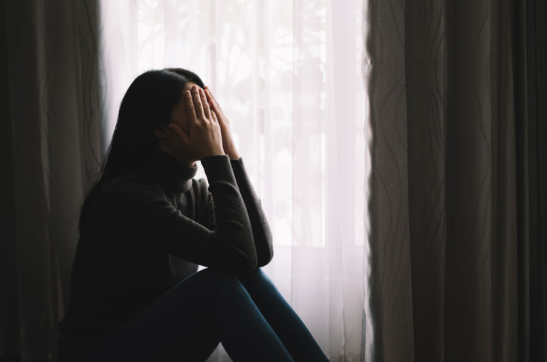 depressive frau, die gesicht mit händen bedeckt