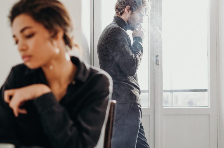 traurige Frau mit Mann im Hintergrund