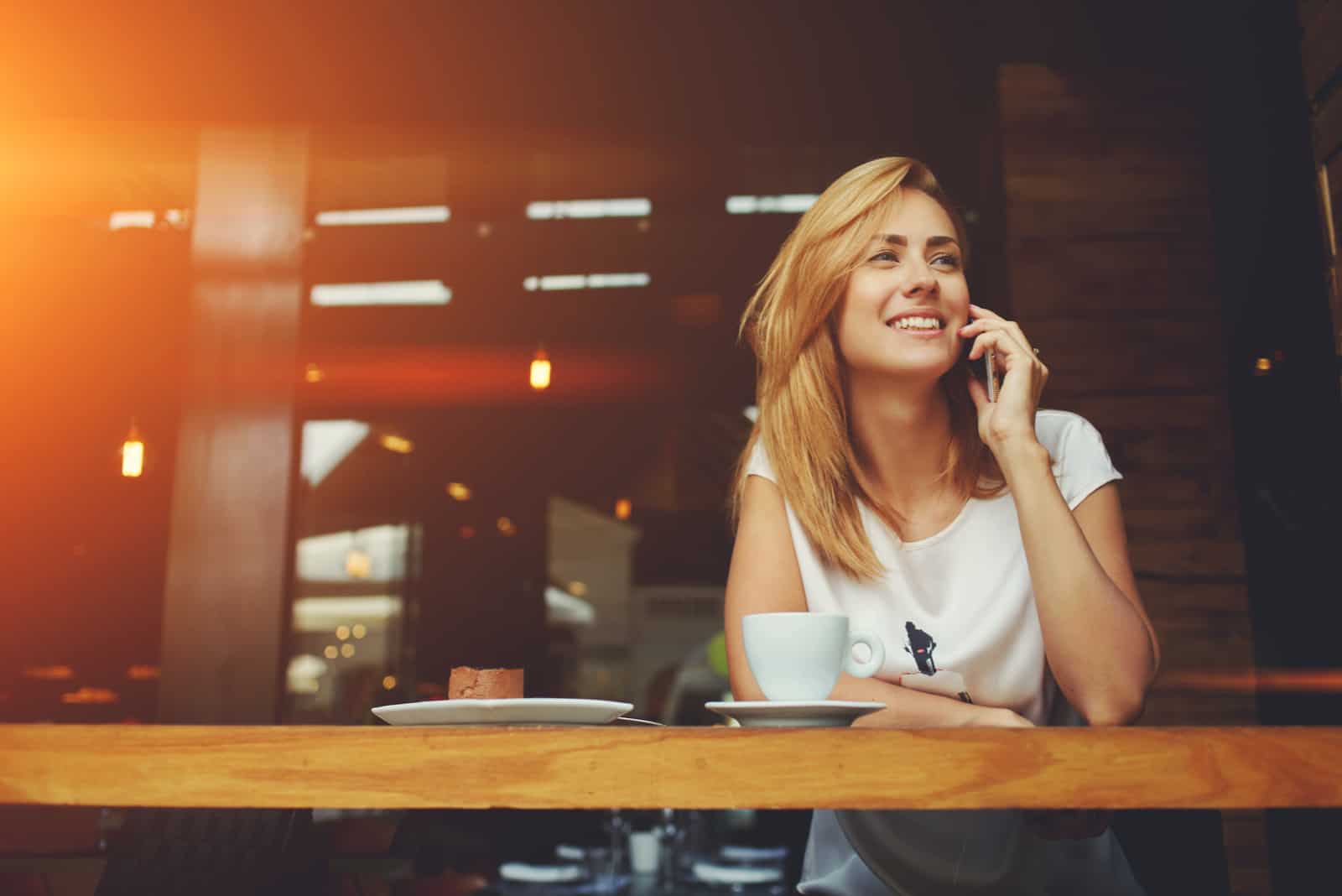 Frau, die mit dem Handy anruft, während sie allein im Café sitzt