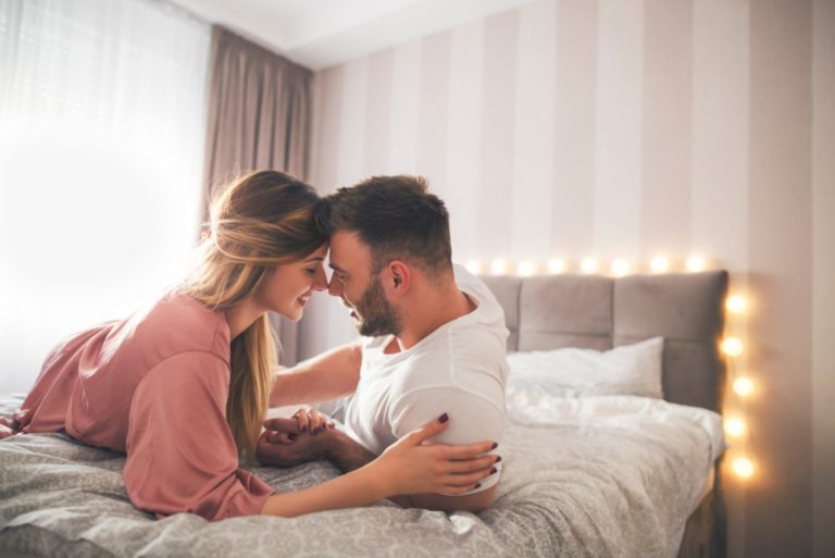 Ein Mann und eine Frau liegen auf dem Bett und tauschen Zärtlichkeit aus
