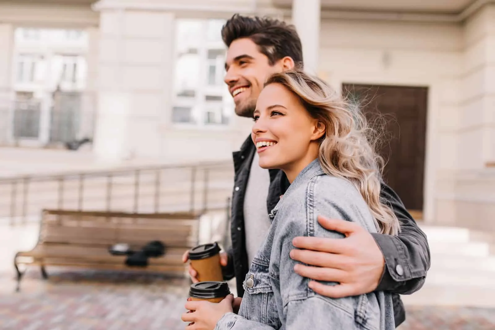 glückliches Paar geht in Umarmung mit Kaffeetassen