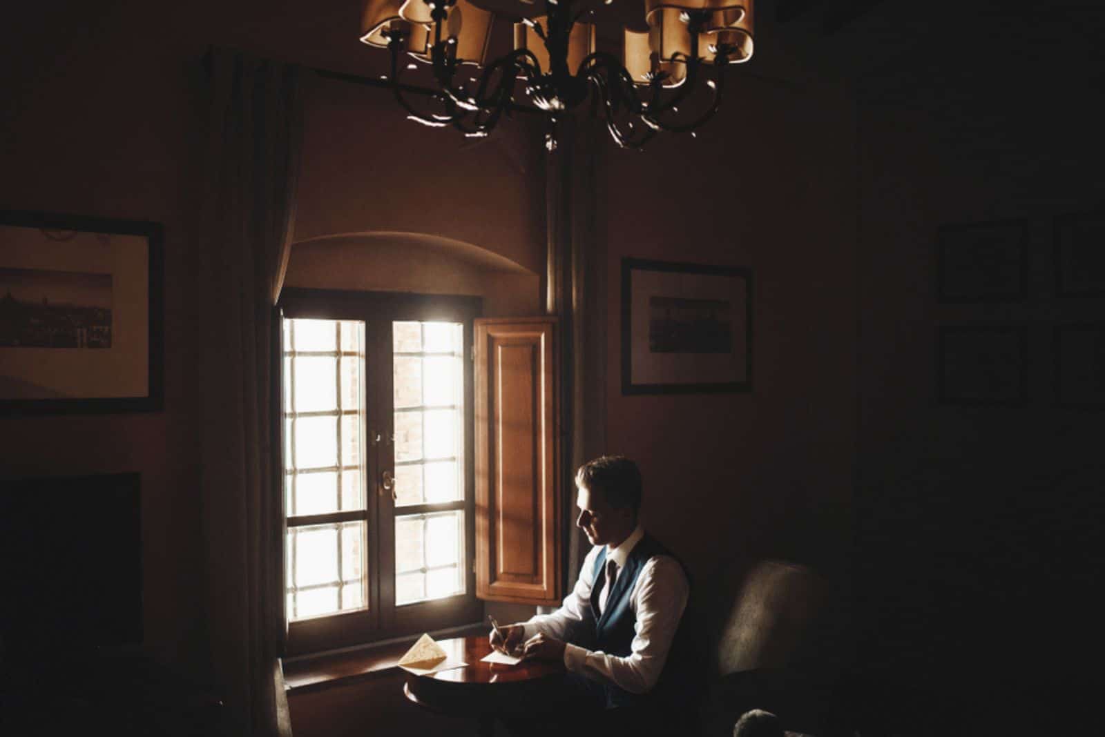 Ein Mann sitzt in einem Café und schreibt einen Brief