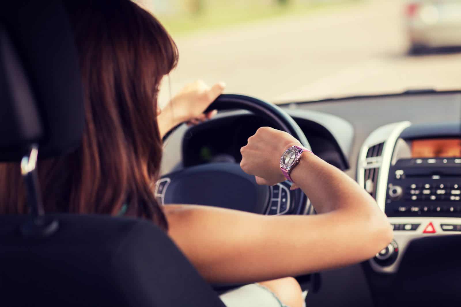 Eine Frau schaut auf ihre Uhr, während sie in einem Auto sitzt