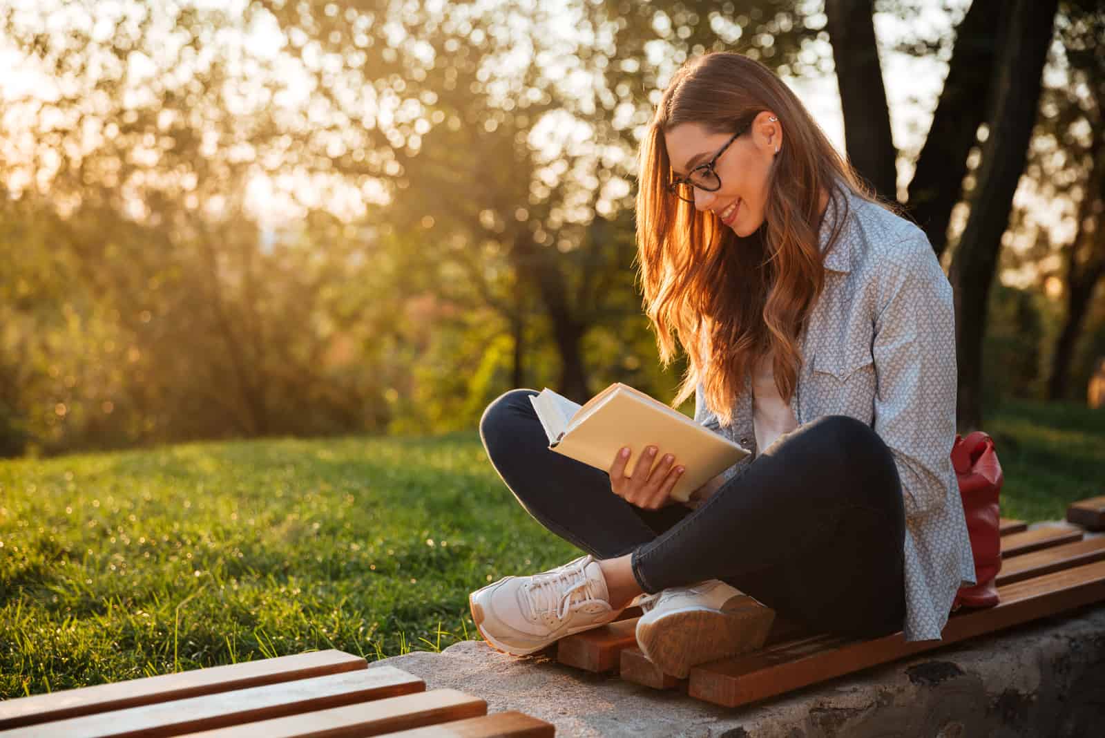 Frau sitzt im Park und liest ein Buch
