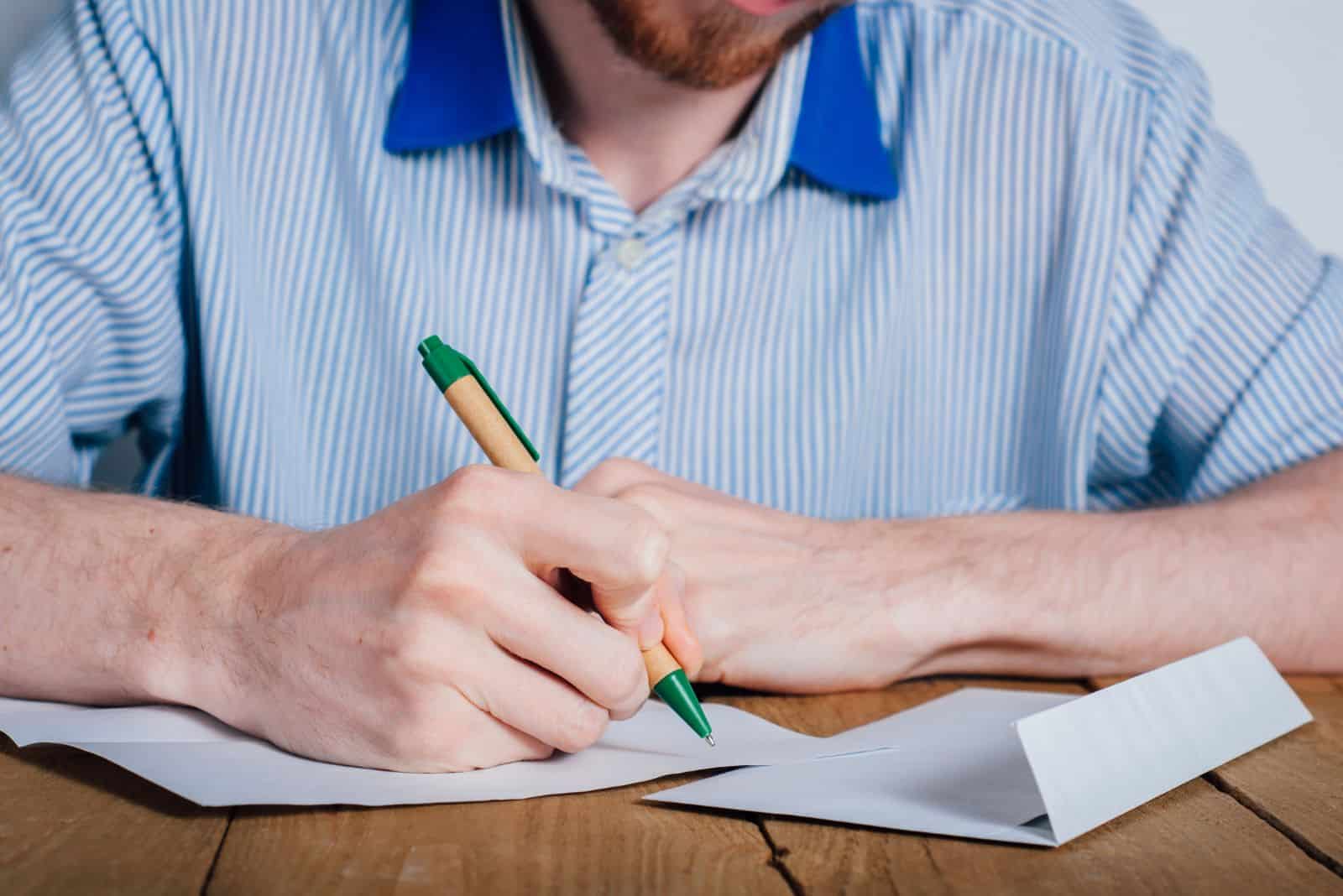 ein mann im hemd sitzt an einem tisch und schreibt einen brief 