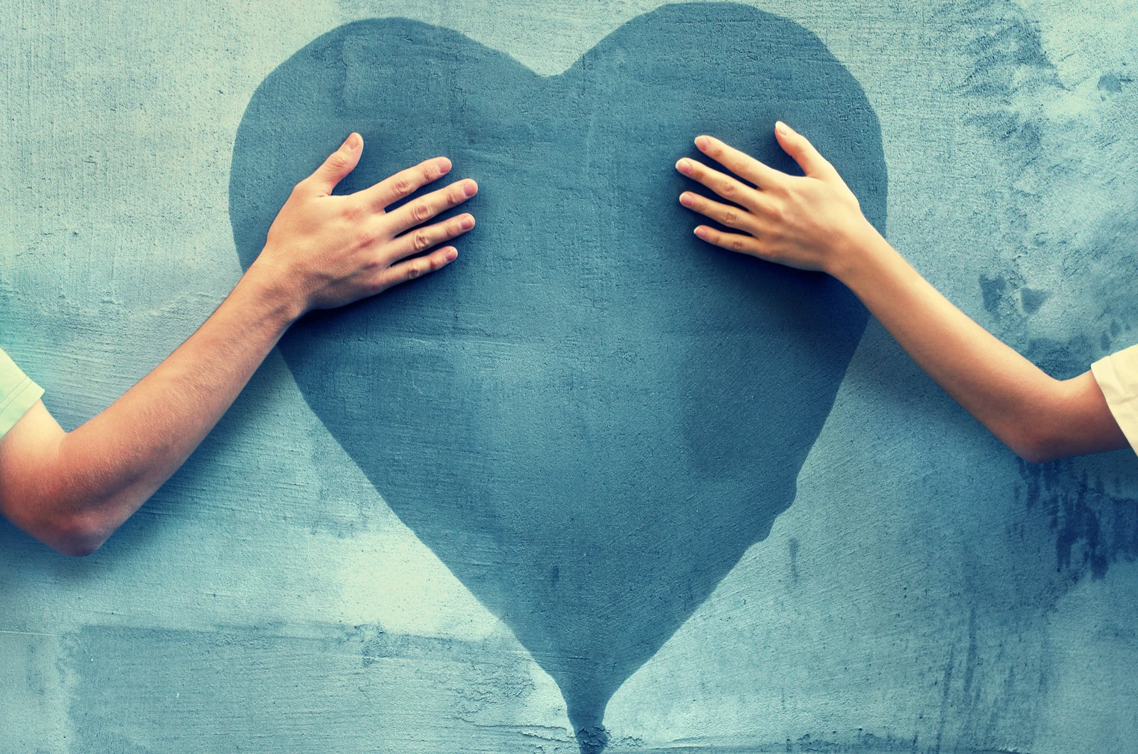 männliche und weibliche Hand berühren blaues Herz